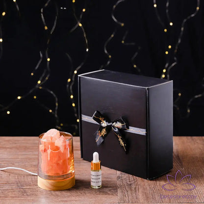 Difusor de aromaterapia AromaLuz com base de madeira, cristal branco iluminado e óleo essencial ao lado, em um ambiente aconchegante.