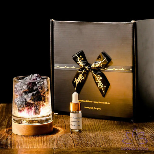 Difusor de aromaterapia AromaLuz com base em madeira e cristal, acompanhado de óleo essencial e embalagem elegante com laço decorativo. Ambiente com luzes decorativas ao fundo.