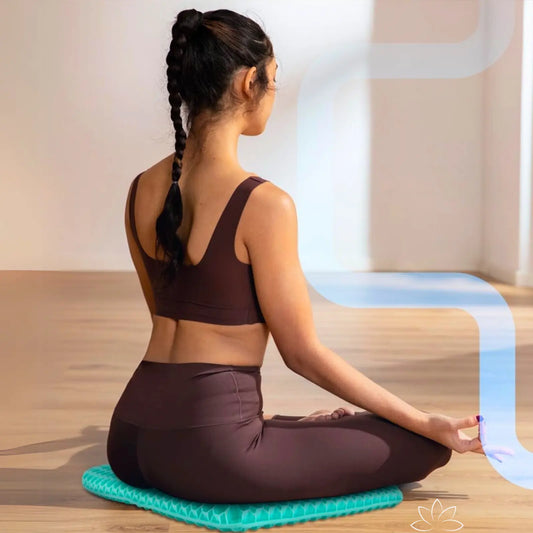 Mulher sentada no chão usando a Almofada FavoGel em posição de yoga